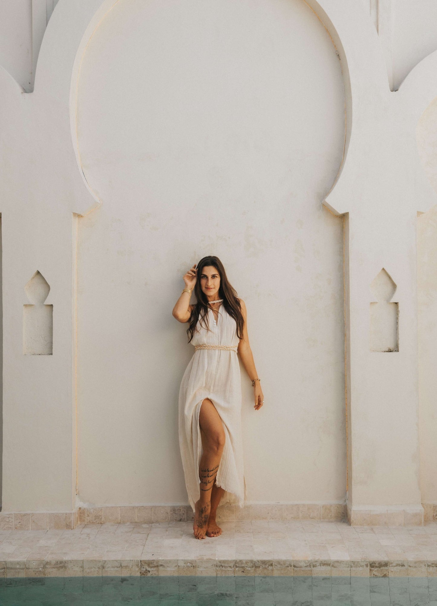 Woman in a white dress standing in front of a white archway