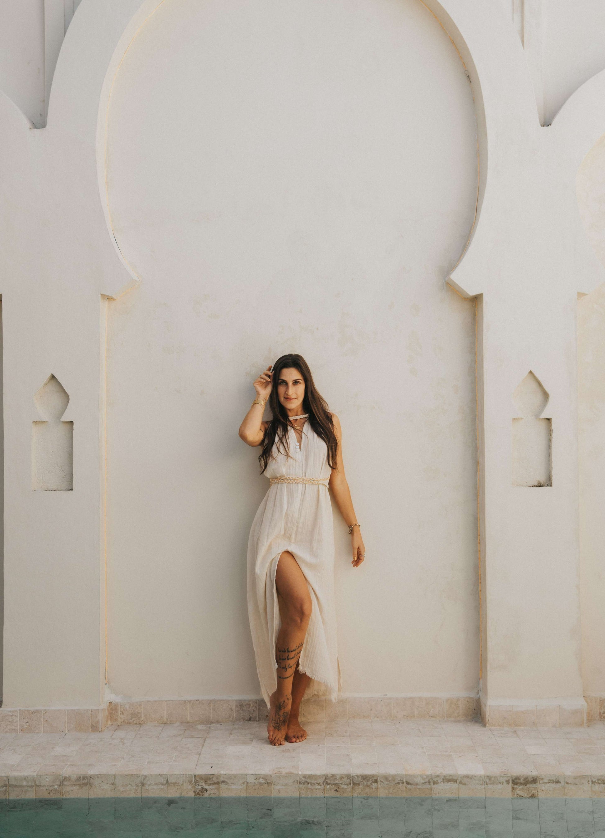 Woman in a white dress standing in front of a white archway