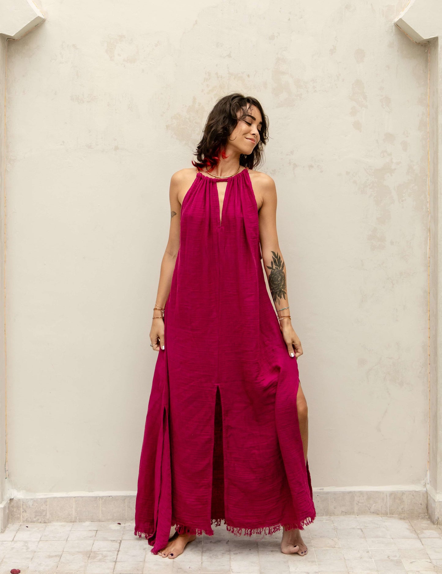 Woman wearing the Delphi Dress — long organic crepe cotton dress with golden Eri silk braids and side slits