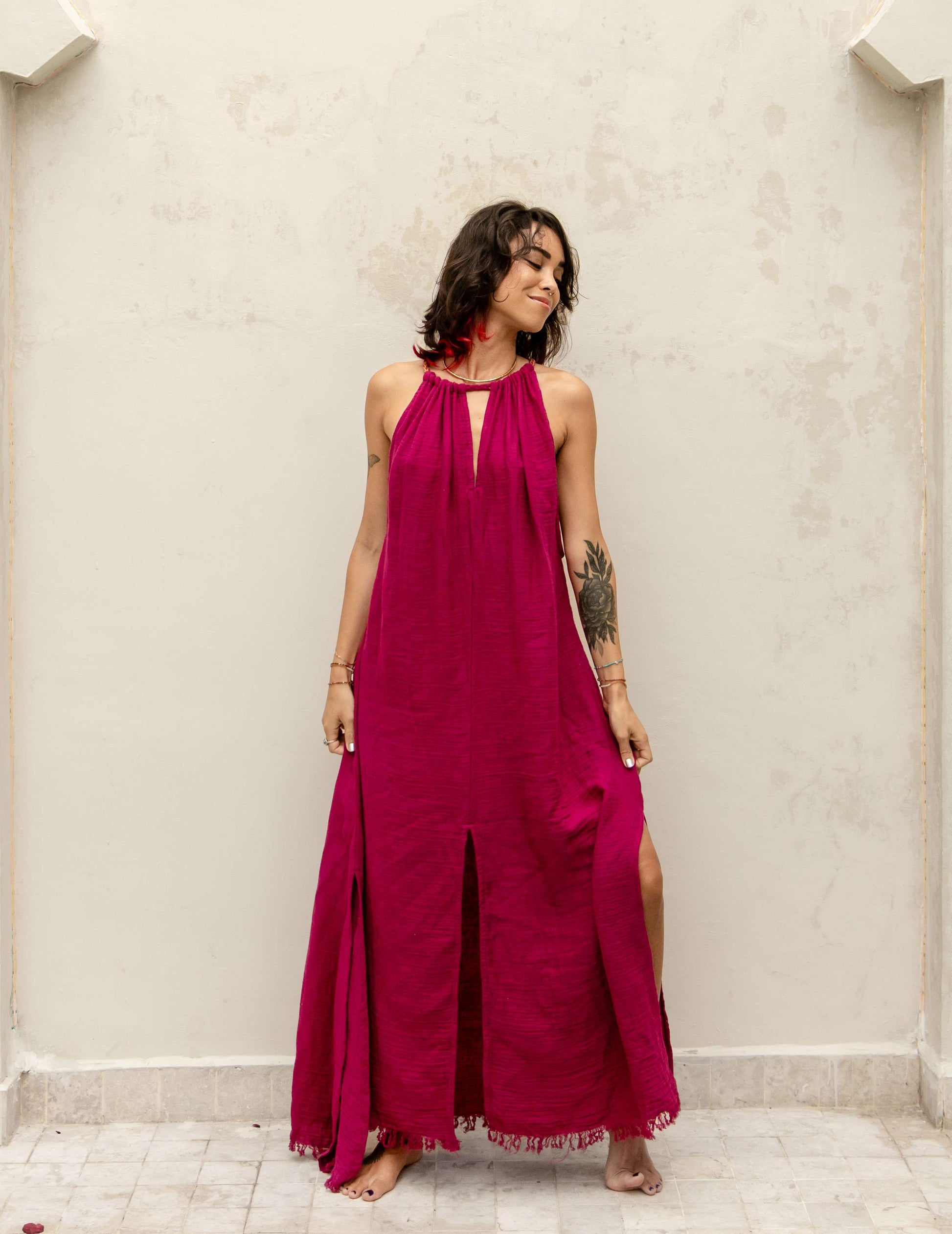 Woman wearing the Delphi Dress — long organic crepe cotton dress with golden Eri silk braids and side slits