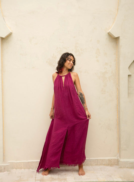 Woman wearing a magenta dress standing against a beige wall.