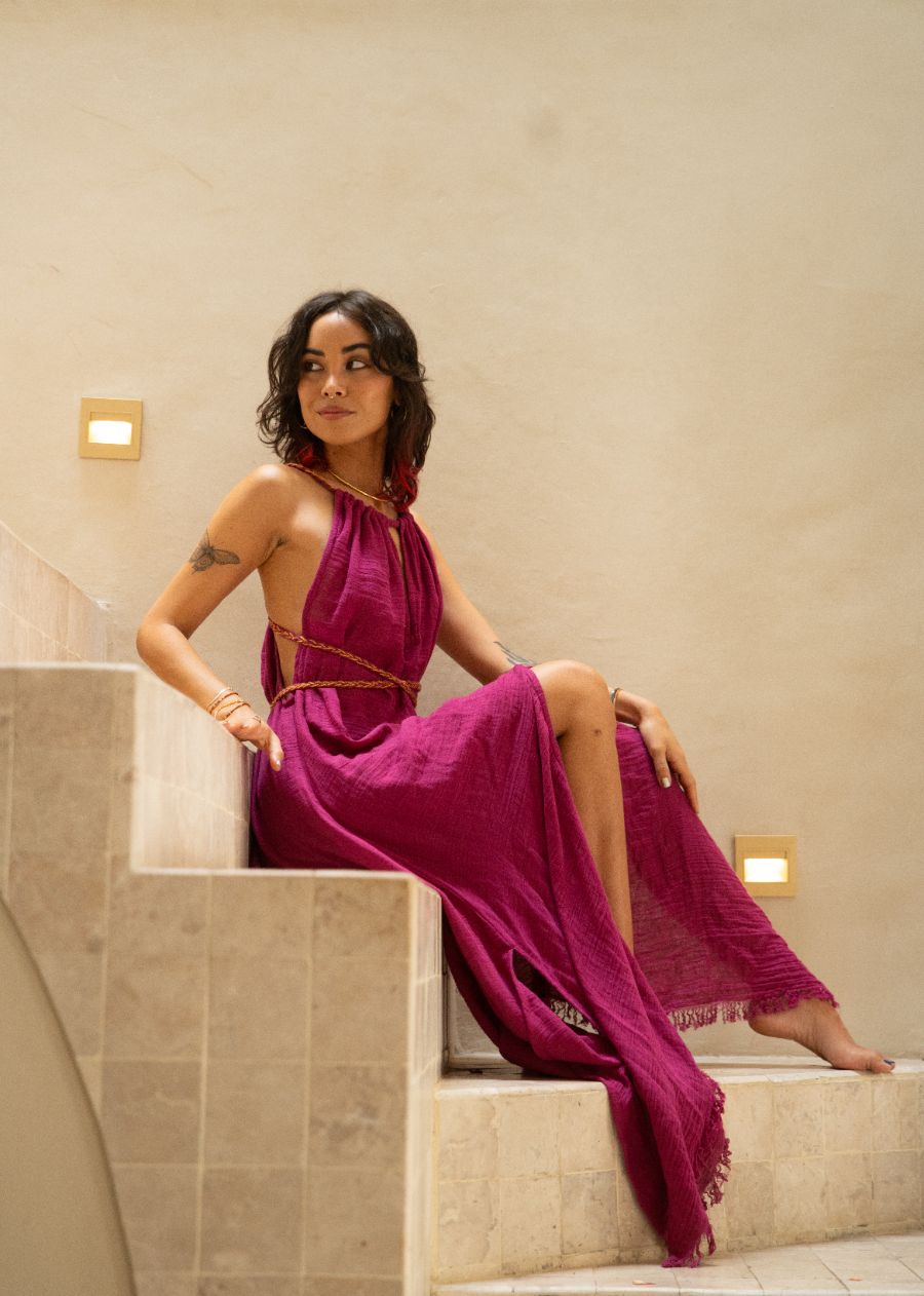Woman in a magenta dress sitting on a staircase in an indoor setting